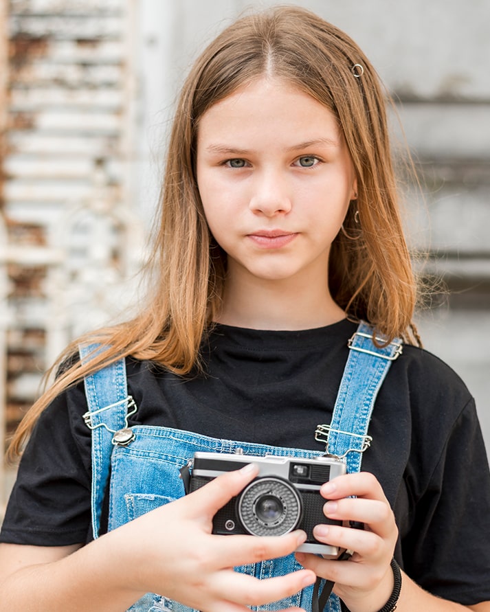 Una noia aguanta una cámera de fotografies antiga